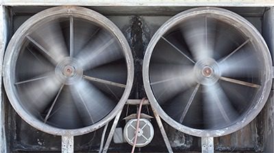 Two large fans are attached to a metal structure.